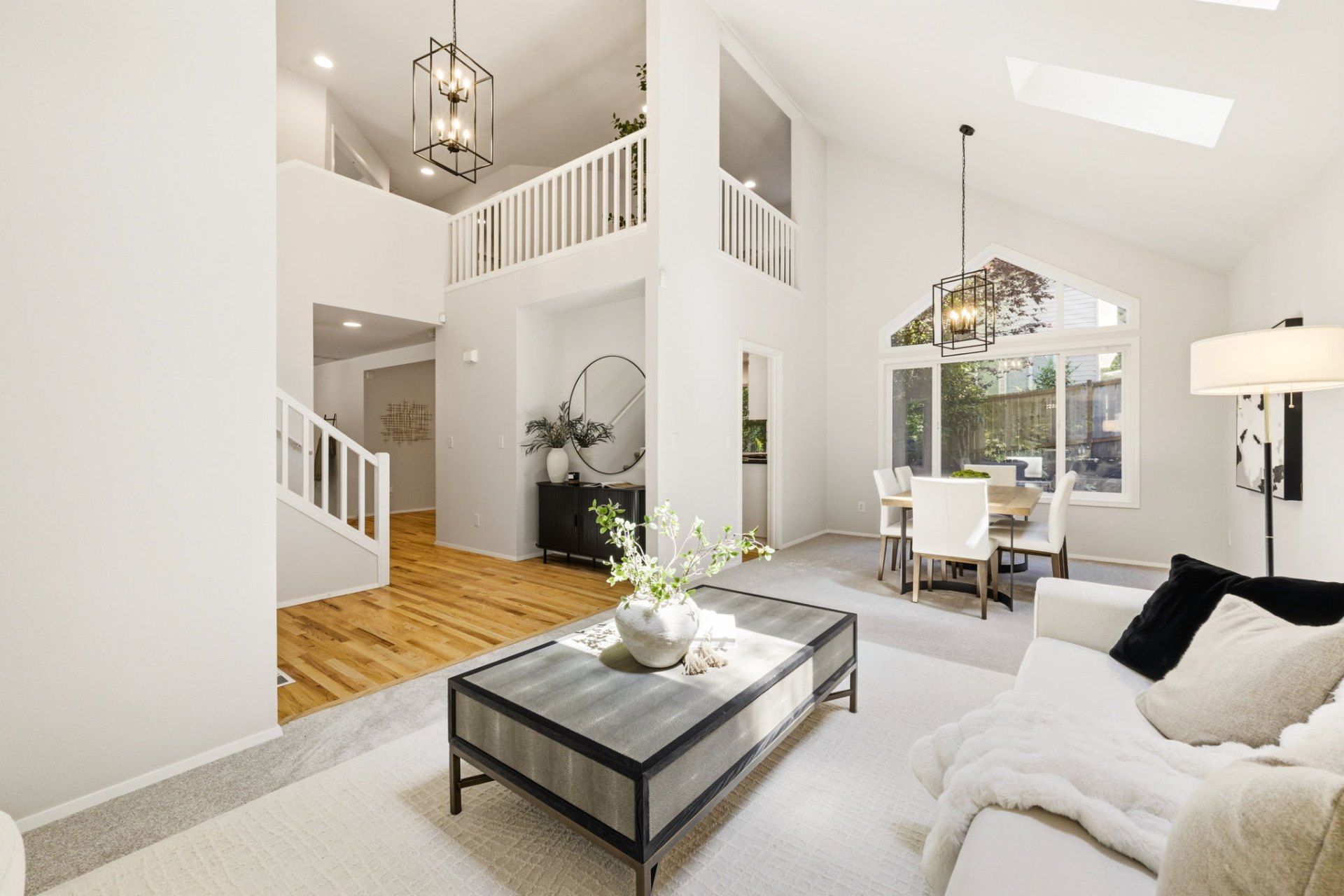 Two-story living room with vaulted ceilings, skylights, and open dining