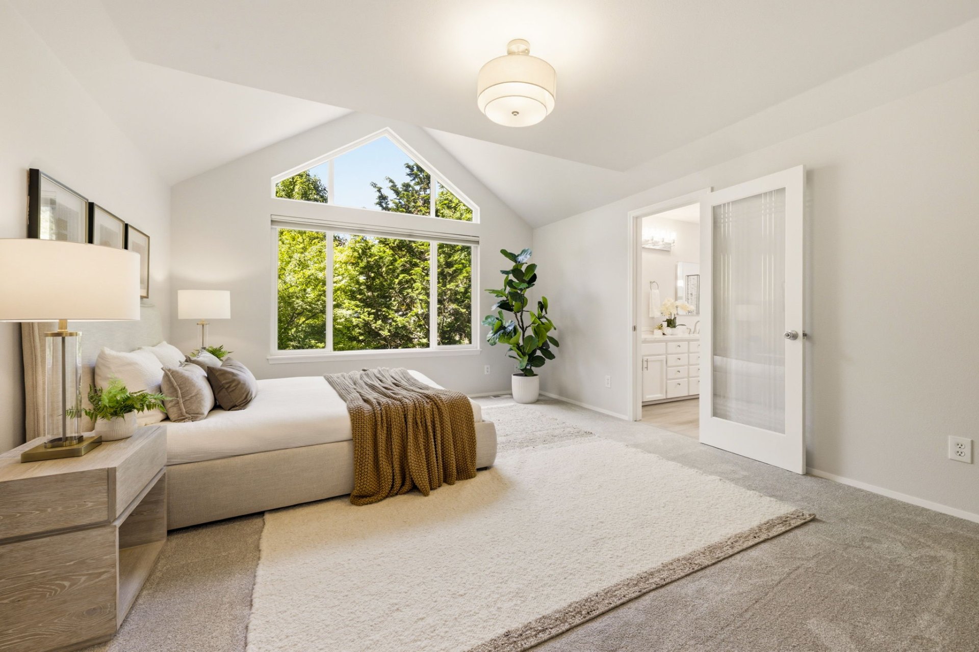 Primary bedroom with vaulted ceilings, gable window, and ensuite bath