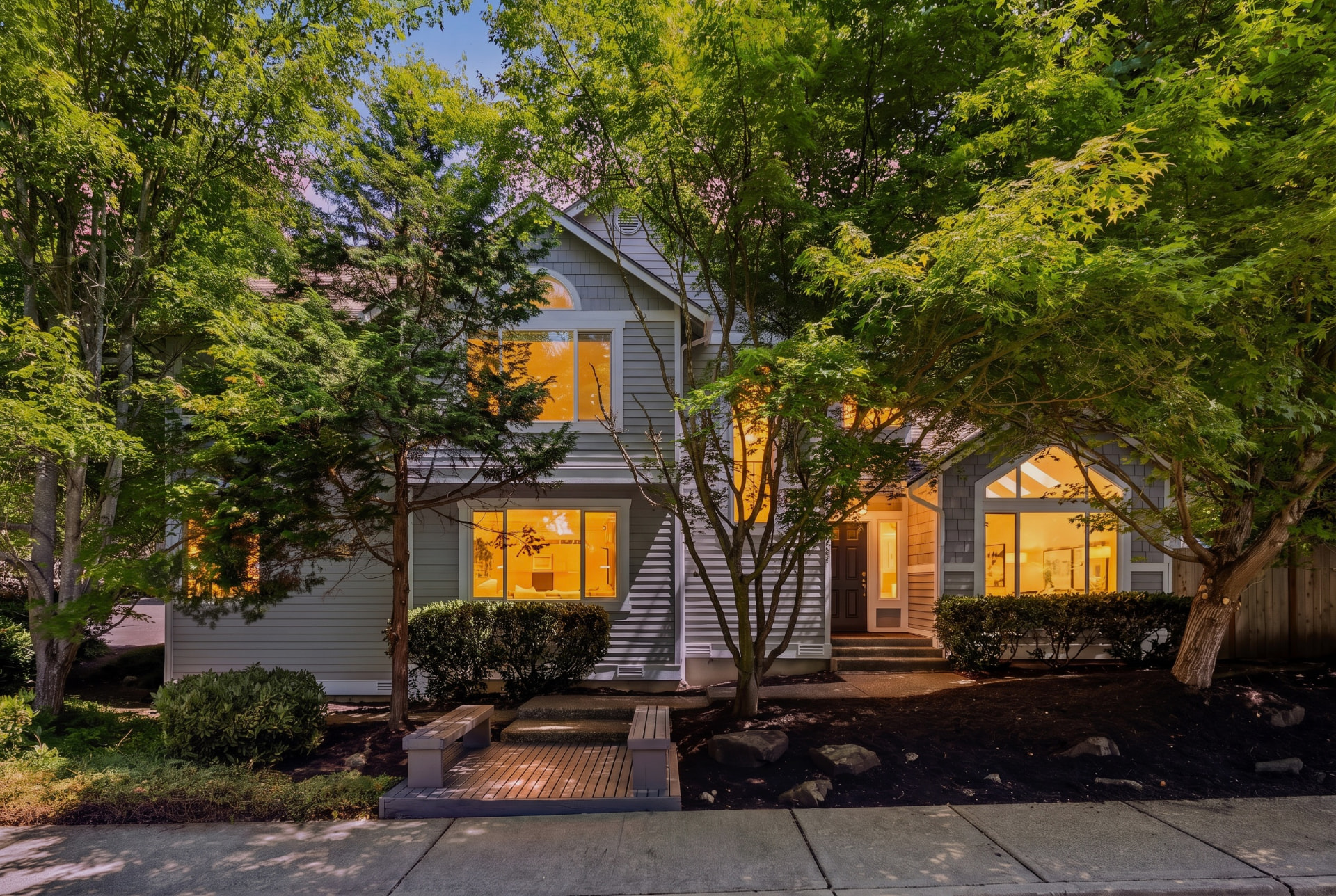 Front exterior of the Juanita corner-lot home at twilight, framed by Japanese maples